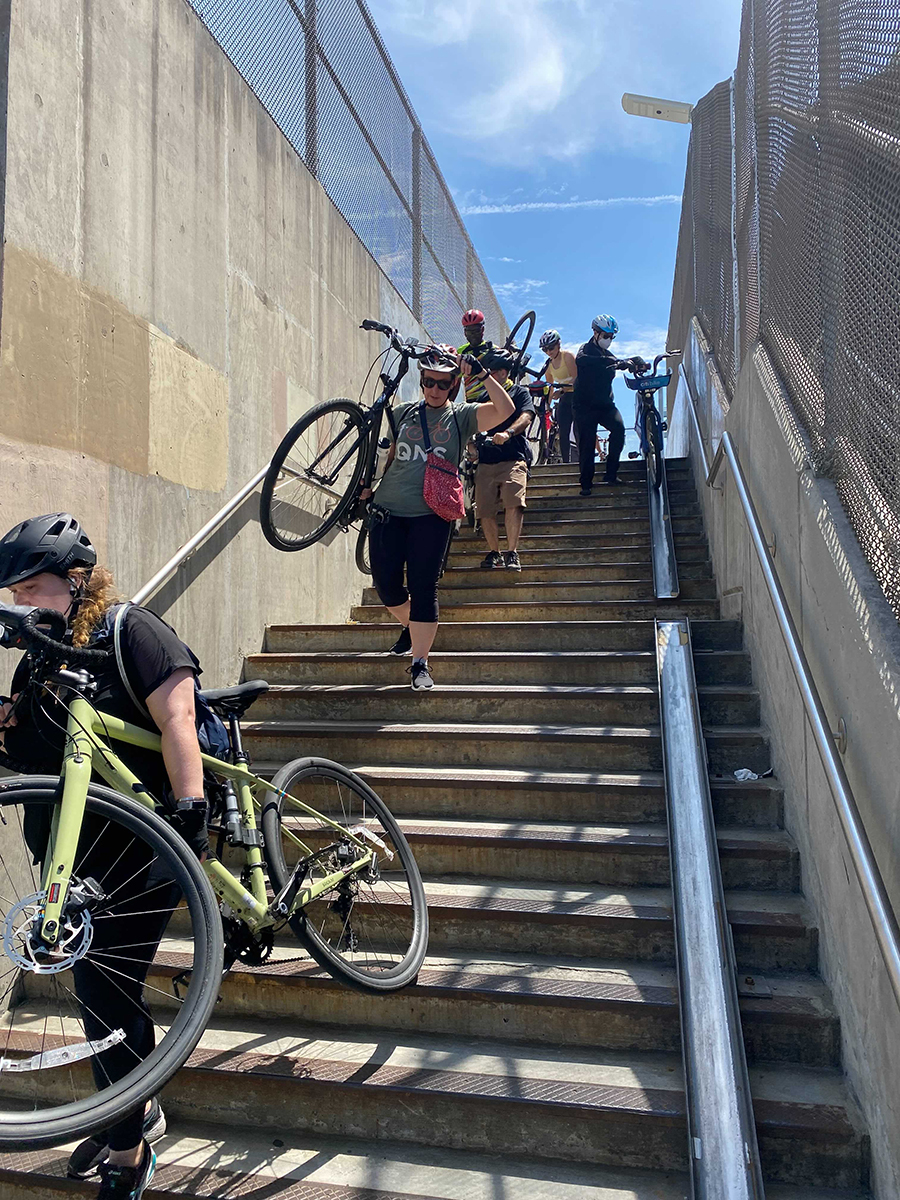 Activists carrying bikes up stairs to cross a bridge